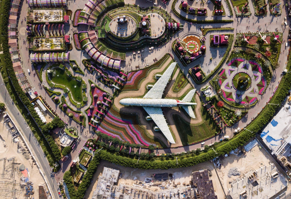 Aerial view of the vibrant and colorful Miracle Garden Dubai, showcasing intricate garden designs, blooming flowers, and a flower-covered airplane.