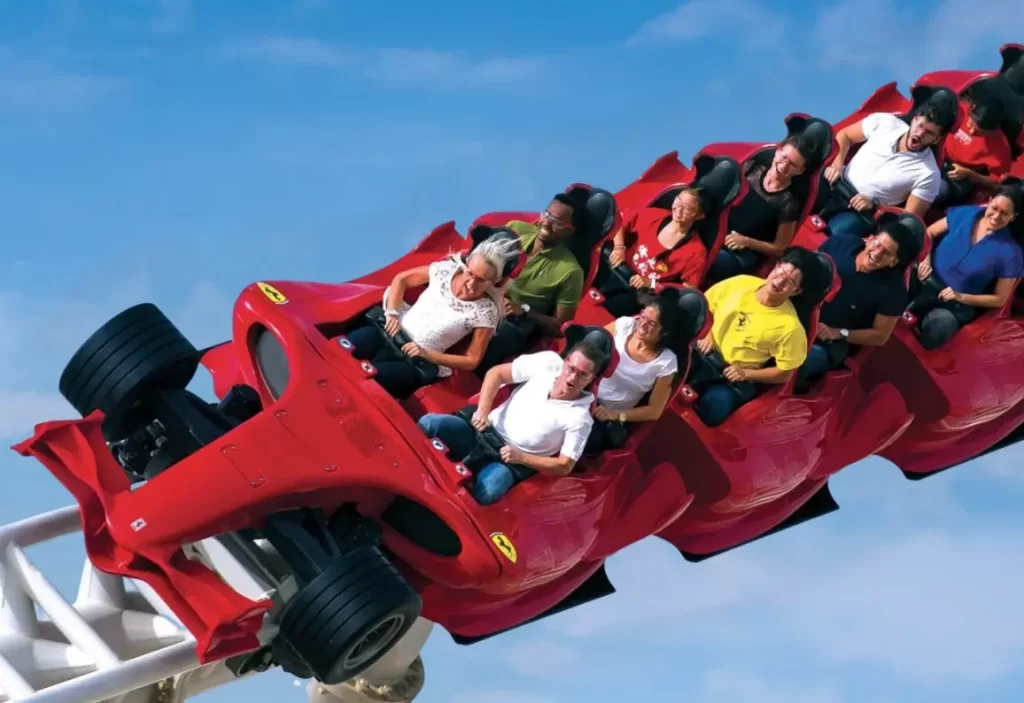 People enjoying a thrilling ride on a red Ferrari-themed roller coaster at Ferrari World Abu Dhabi.
