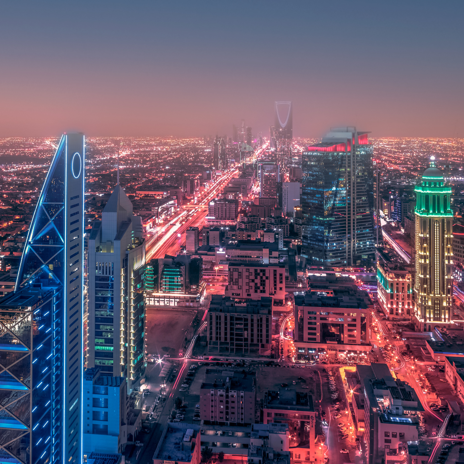 Stunning aerial view of Riyadh at dusk with illuminated skyscrapers and bustling city streets.